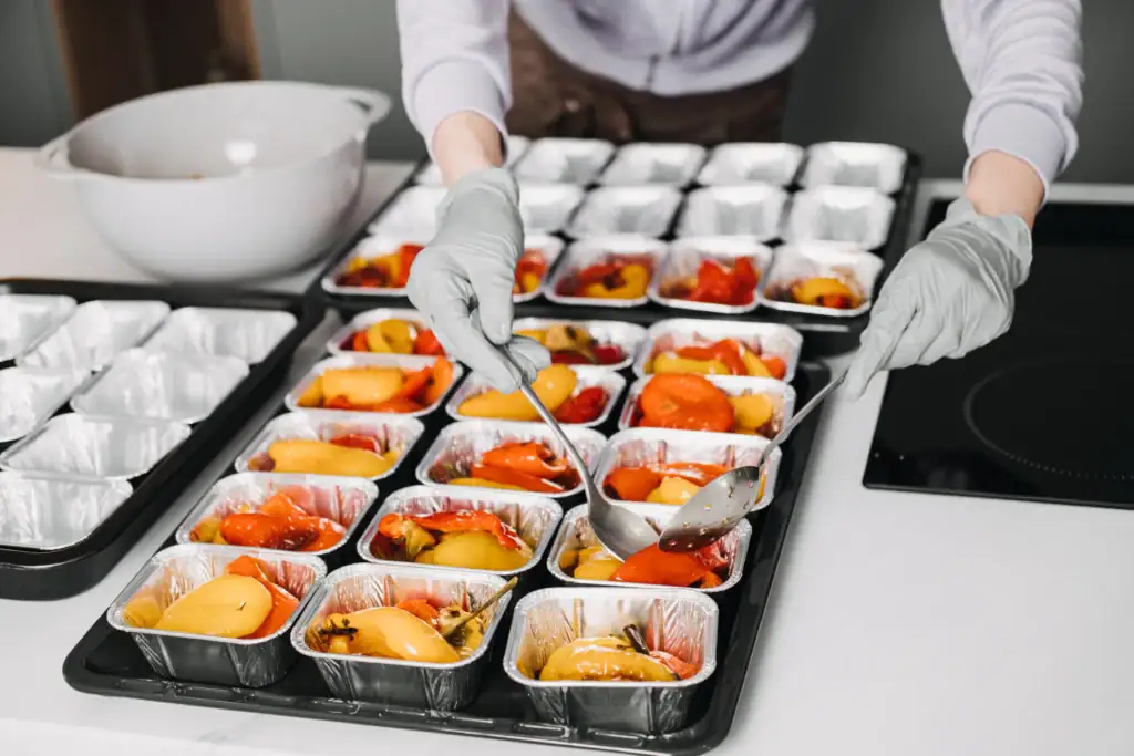 Preparazione di piatti in contenitori monouso in TNT per catering e ristorazione.